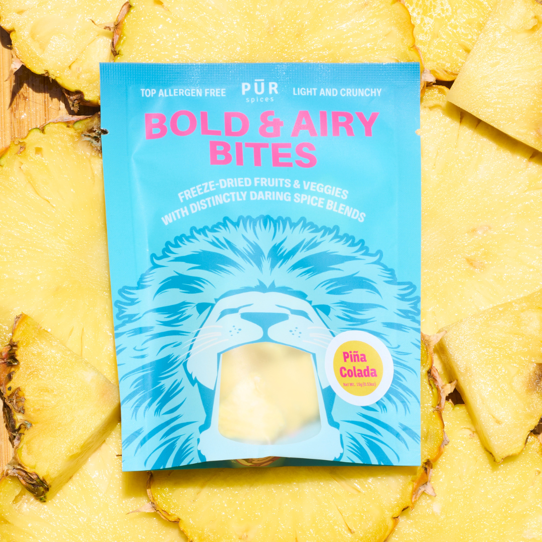 Packaging of Piña Colada flavored freeze-dried bites surrounded by pineapple slices.